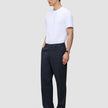 A man wearing a white t-shirt and Atelier Pants Relaxed Dark Navy, which are relaxed-fit, heavyweight broken twill trousers.
