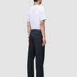A man seen from behind wearing a white t-shirt and Atelier Pants Relaxed Dark Navy in heavyweight broken twill, paired with black shoes.