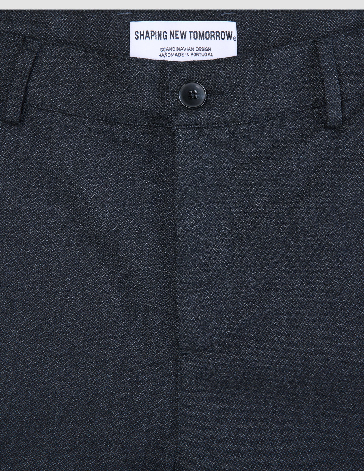 Close-up of Atelier Pants Relaxed Dark Navy, featuring a relaxed fit, button closure, and an interior brand label reading Shaping New Tomorrow.