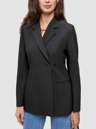 A person wearing a black double-breasted Women’s Avira Blazer over blue jeans.