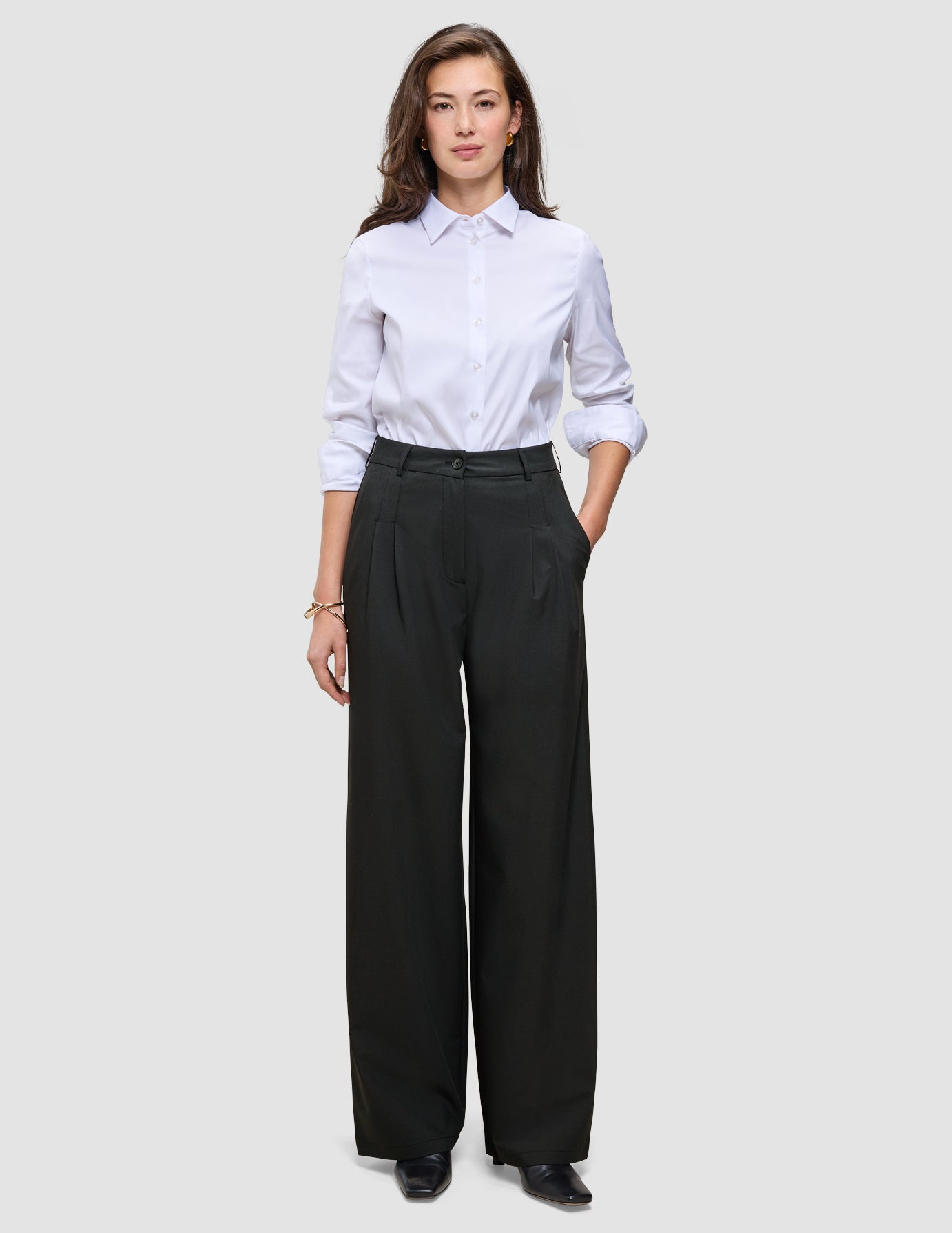 A woman wearing a crisp white button-down shirt and black Women’s Avira Pants Wide.