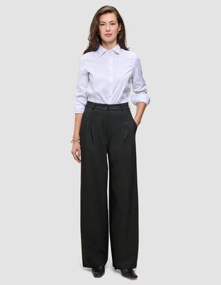 A woman wearing a crisp white button-down shirt and black Women’s Avira Pants Wide.