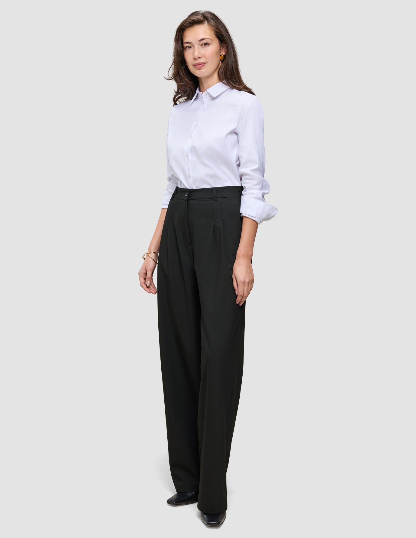 A person wearing a white button-down shirt tucked into black Women’s Avira Pants Wide Black.