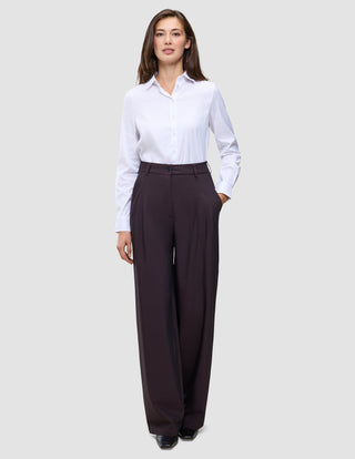 A woman wearing a crisp white button-down shirt tucked into Women’s Avira Pants Wide Burgundy Berry.