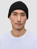 A person wearing a black merino wool rib knit Beanie Black.