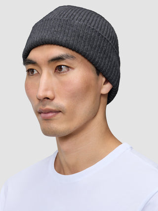 A man wearing a dark grey merino wool rib knit Beanie Dark Grey.