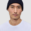 A man wearing a Wool Beanie Navy, a navy blue merino wool rib knit beanie.