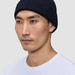 A person wearing a navy blue Wool Beanie Navy in a rib knit merino wool style.