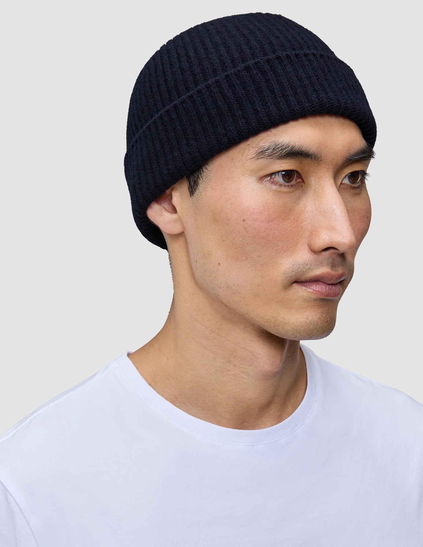 A person wearing a navy blue rib knit Wool Beanie Navy.