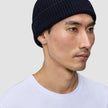 A person wearing a navy blue rib knit Wool Beanie Navy.
