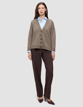 A woman wearing a Women’s Chunky Soft Wool Knit Cardigan Taupe Melange over a light blue button-down shirt, paired with dark brown trousers and matching heels.