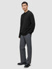 A man wears a Chunky Soft Wool Knit Crewneck Black sweater of Scandinavian design with grey trousers.