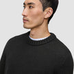 A man wearing a black Chunky Soft Wool Knit Crewneck over a white shirt, reflecting a clean Scandinavian design.