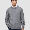 A man wearing a Chunky Soft Wool Knit Crewneck Glacier Grey sweater over a white collared shirt.
