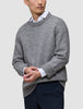 A person wearing a Chunky Soft Wool Knit Crewneck Glacier Grey over a white collared shirt and dark trousers.