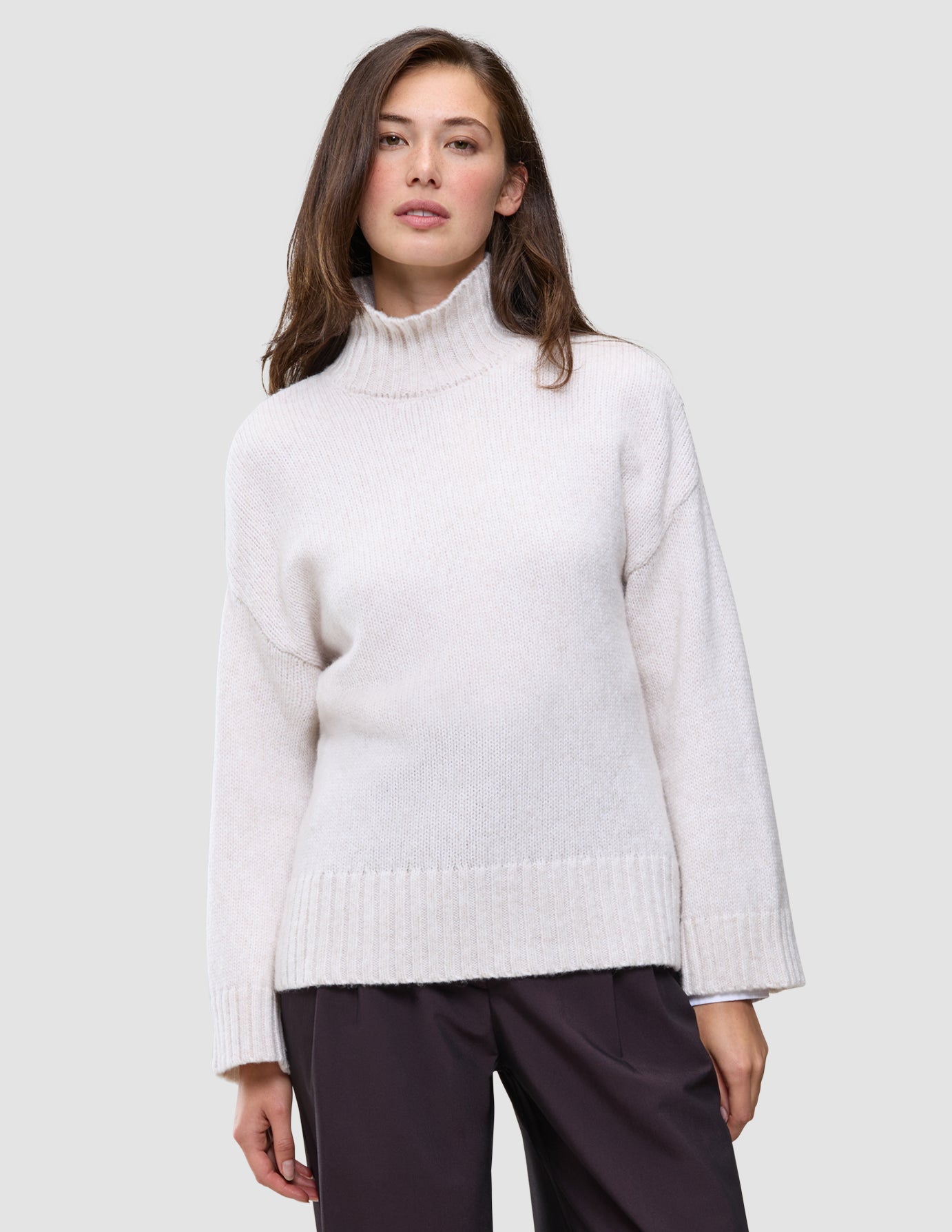 Woman wearing an off-white, chunky wool Women’s Chunky Soft Wool Knit Turtleneck Sugar Melange with long sleeves in a Scandinavian knit.