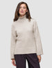 A woman wearing the Women’s Chunky Soft Wool Knit Turtleneck Sugar Melange, an oversized, light beige merino wool sweater with ribbed cuffs and hem in a minimalist Scandinavian design.