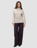 A person wearing a Women’s Chunky Soft Wool Knit Turtleneck Sugar Melange in beige and dark wide-leg trousers.