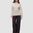 A person wearing a Women’s Chunky Soft Wool Knit Turtleneck Sugar Melange in beige and dark wide-leg trousers.