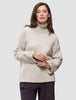 A woman wearing a Women’s Chunky Soft Wool Knit Turtleneck Sugar Melange, an oversized, light beige merino wool sweater with ribbed cuffs and hem, showcasing a minimalist Scandinavian design.