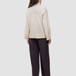Back view of a person wearing a Women’s Chunky Soft Wool Knit Turtleneck Sugar Melange in an oversized, chunky knit style with dark wide-leg trousers.