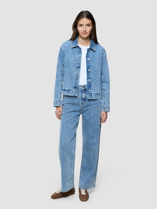 A woman wearing a white t-shirt, a Women’s Classic Denim Jacket Snow Blue Wash, and matching loose-fit jeans.