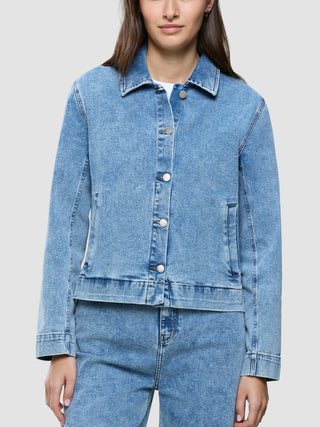 A person wearing a Women’s Classic Denim Jacket Snow Blue Wash buttoned over matching denim bottoms.