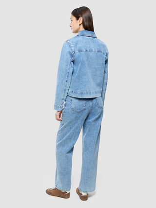 A person seen from behind, wearing a Women’s Classic Denim Jacket Snow Blue Wash and matching jeans.