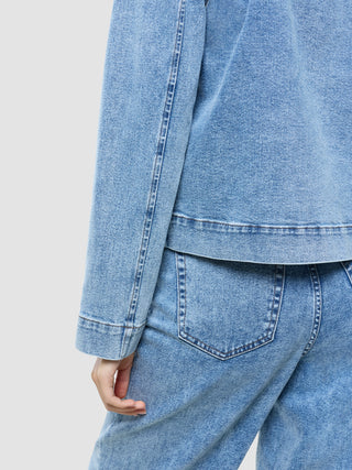 A person wearing a Women’s Classic Denim Jacket Snow Blue Wash and matching jeans.