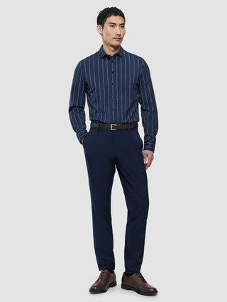 A man wearing a Classic Shirt Midnight Pinstripes Regular, navy trousers, a brown leather belt, and brown dress shoes.