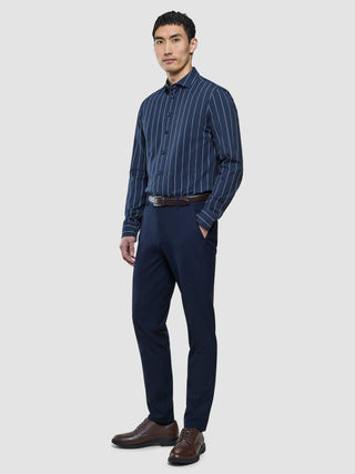 A man wearing a Classic Shirt Midnight Pinstripes Regular, navy trousers, a brown belt, and brown dress shoes.