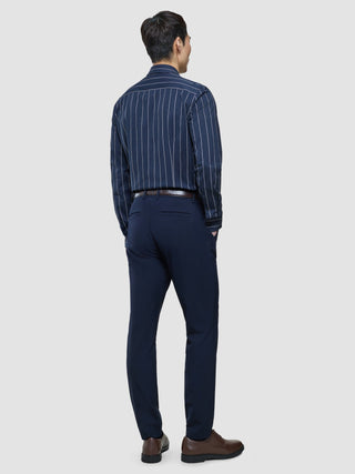 A man stands facing away, wearing a Classic Shirt Midnight Pinstripes Regular tucked into dark trousers and brown shoes.