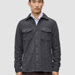 A man wearing a Double Layer Wool Overshirt Regular Dark Grey in a Scandinavian-design wool-blend with two chest pockets, layered over a white collared shirt.