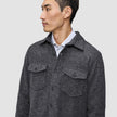 A man wearing a Double Layer Wool Overshirt Regular Dark Grey in a Scandinavian design over a white collared shirt.