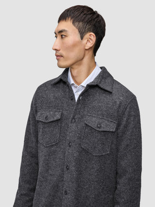 A man wearing a Double Layer Wool Overshirt Regular Dark Grey in a Scandinavian design over a white collared shirt.