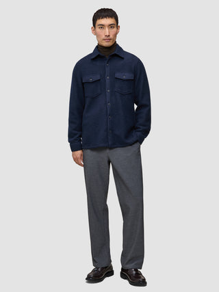 A man wears a Double Layer Wool Overshirt Regular Dark Navy over a brown turtleneck, paired with grey trousers and dark loafers.
