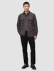 A man wearing a Double Layer Wool Overshirt Saddle Brown over a grey t-shirt, black trousers, and black loafers, reflecting a clean Scandinavian design.
