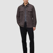 A man wearing a Double Layer Wool Overshirt Saddle Brown over a grey t-shirt, black trousers, and black loafers, reflecting a clean Scandinavian design.