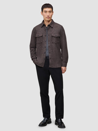 A man wearing a Double Layer Wool Overshirt Saddle Brown over a grey t-shirt, black trousers, and black loafers, reflecting a clean Scandinavian design.
