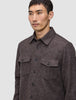 A man wears a brown Double Layer Wool Overshirt, featuring a button-up, double-layer design with two chest pockets with buttoned flaps.