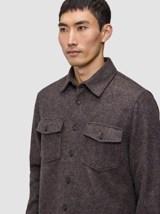 A man wears a brown Double Layer Wool Overshirt, featuring a button-up, double-layer design with two chest pockets with buttoned flaps.