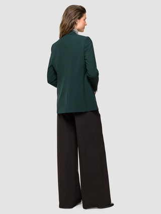 A woman seen from behind wearing a Women Ease Blazer Evergreen and dark wide-leg trousers.