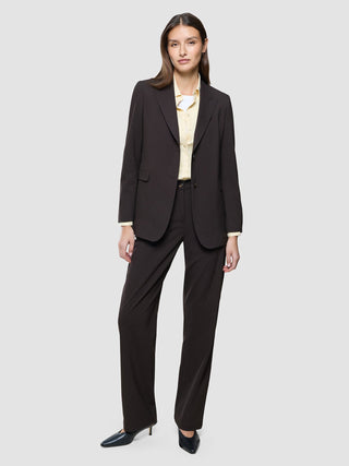 A woman wears a Women Ease Blazer Mocha Melange and matching trousers over a pale yellow button-down shirt.