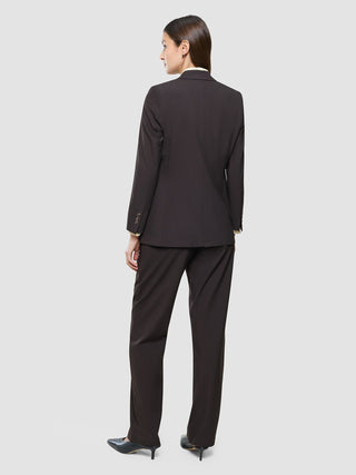 A woman seen from behind wearing a Women Ease Blazer Mocha Melange over a light-colored collared shirt and black heels, embodying a minimalist Scandinavian design.