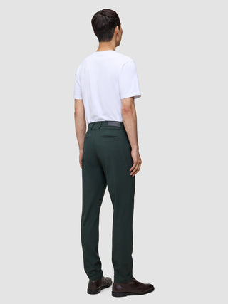 A man seen from behind wearing a white t-shirt, Ease Pants Regular Northern Pine, and brown leather shoes.