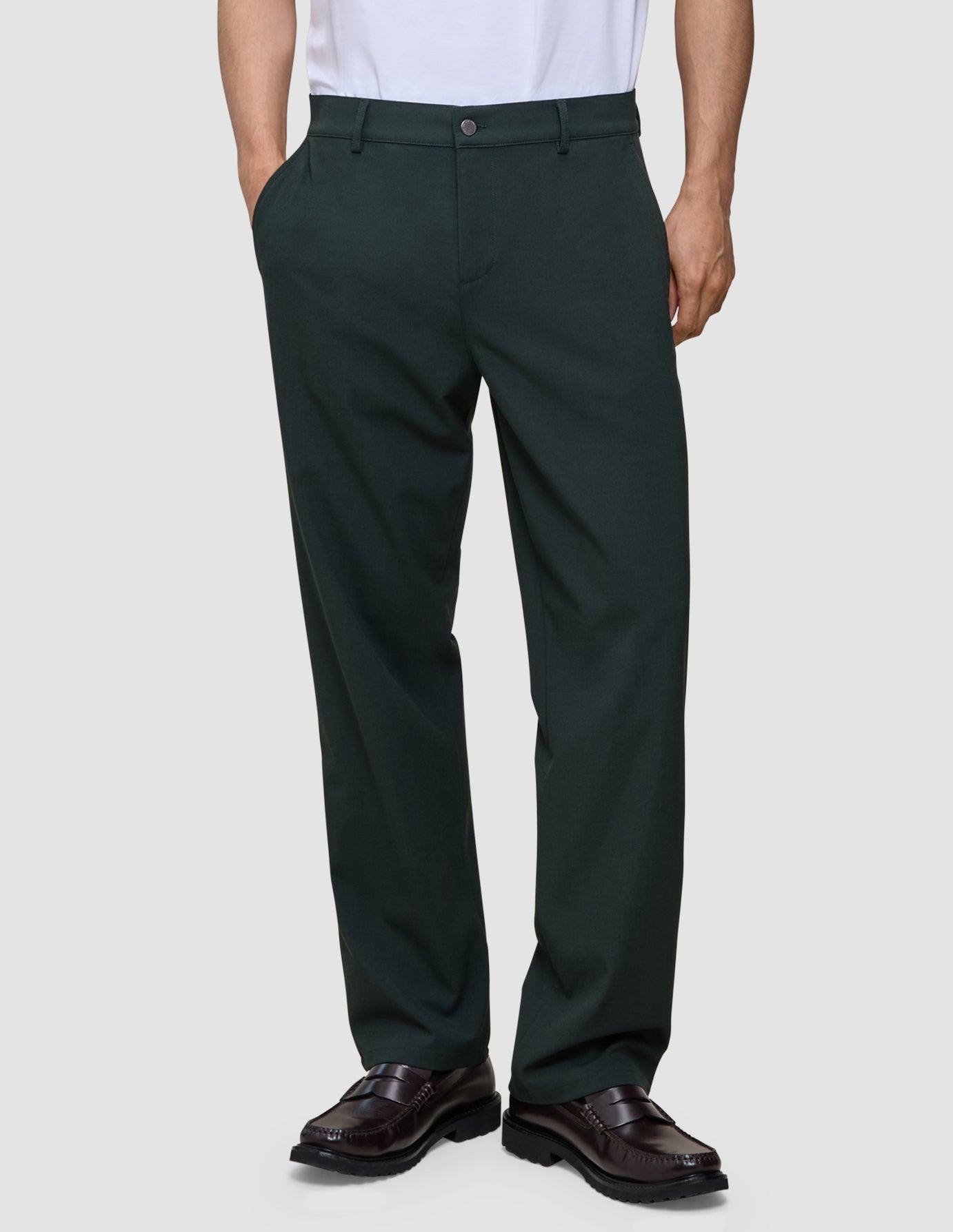 A person wearing exceptionally soft, dark green Ease Pants Relaxed Fit Northern Pine trousers and brown loafers.
