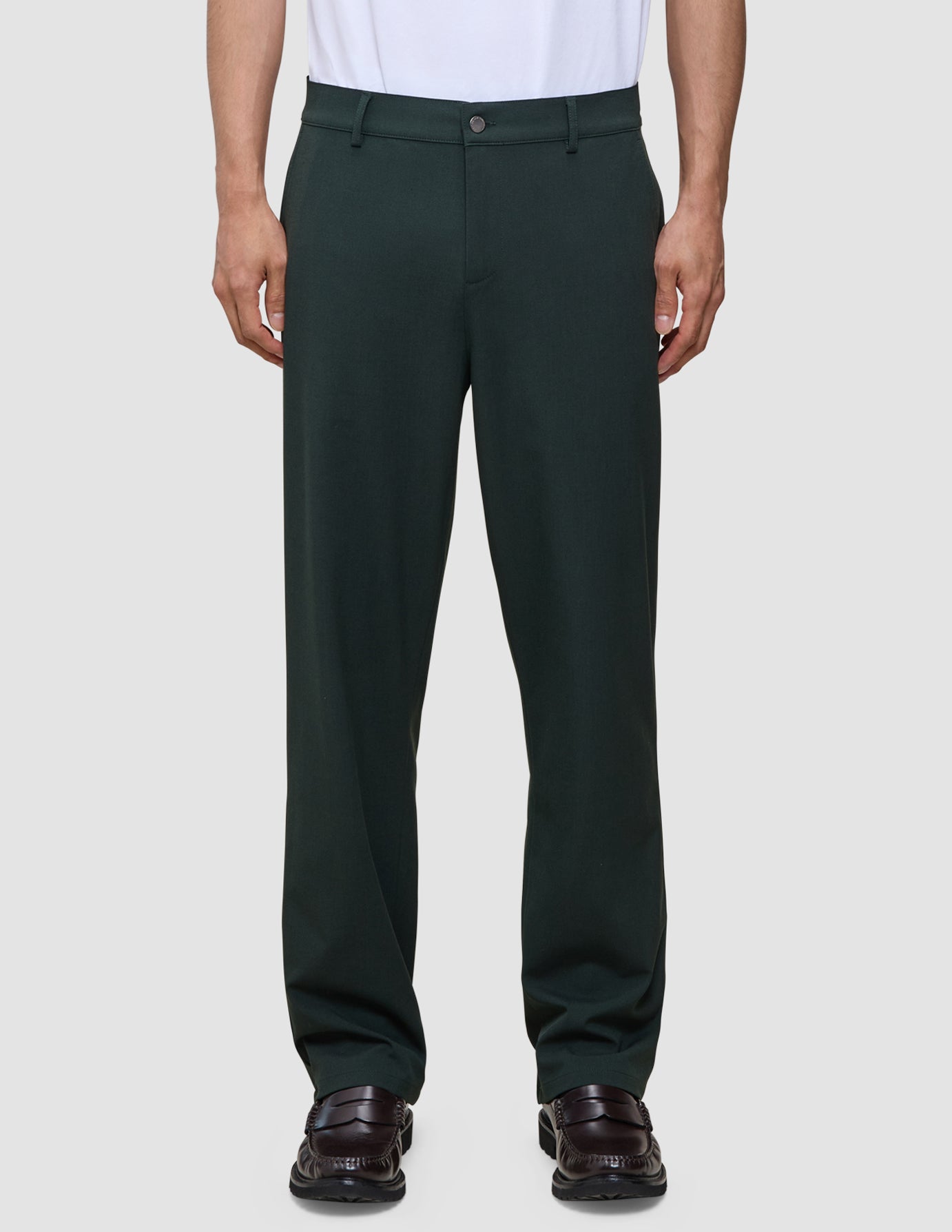 Person wearing exceptionally soft, dark green Ease Pants Relaxed Fit Northern Pine tailored trousers and dark loafers.