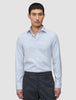 A man wearing an Elevated Shirt Regular Classic Blue Striped light blue and white pinstriped Pima cotton shirt tucked into dark grey trousers.