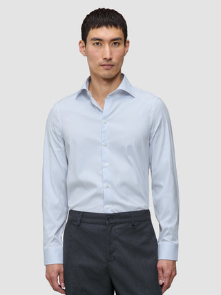 A man wearing an Elevated Shirt Regular Classic Blue Striped light blue and white pinstriped Pima cotton shirt tucked into dark grey trousers.
