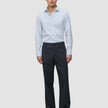 A man wearing an Elevated Shirt Regular Classic Blue Striped light blue pinstriped Pima cotton button-down shirt, dark trousers, and black loafers.